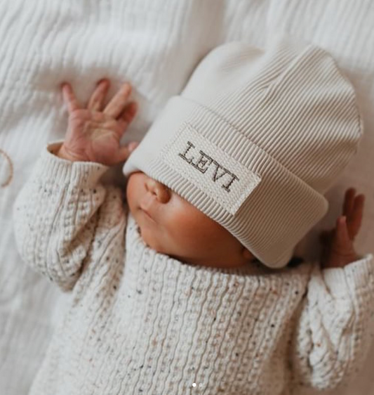 Mutsje met naam ecru, ecru label en beige donkere letters 