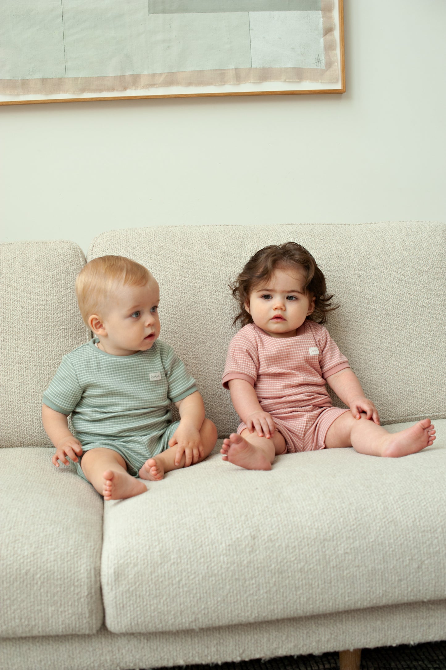 Baby draagt mauve Feetje shortama op bank in zomerse setting
