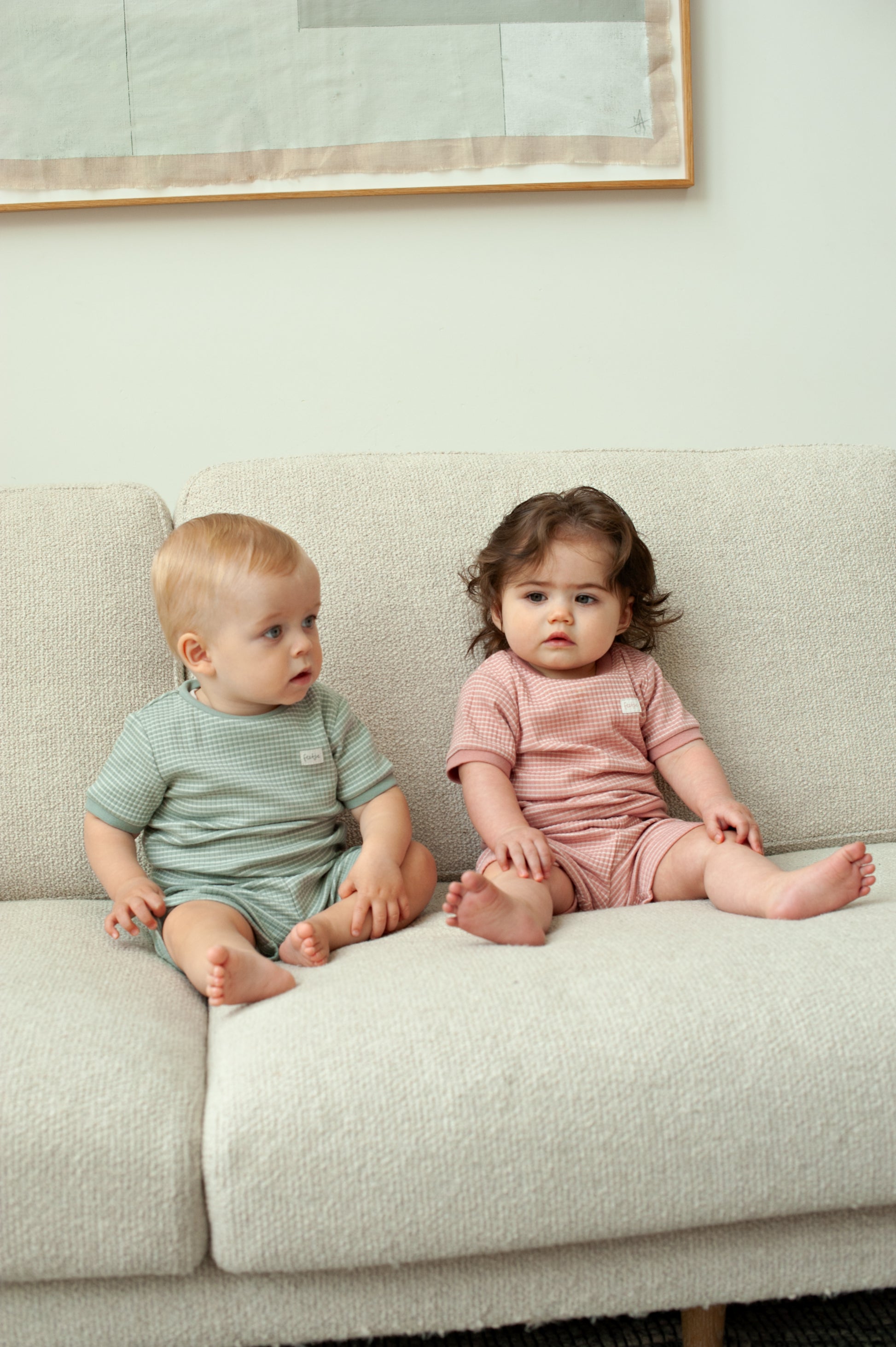 Baby draagt mauve Feetje shortama op bank in zomerse setting